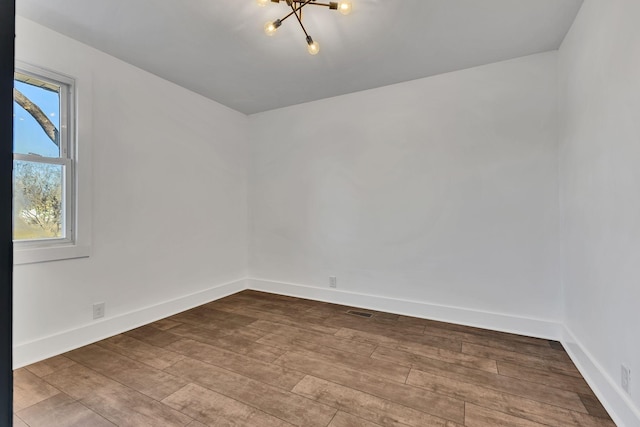 empty room with light hardwood / wood-style floors and a chandelier