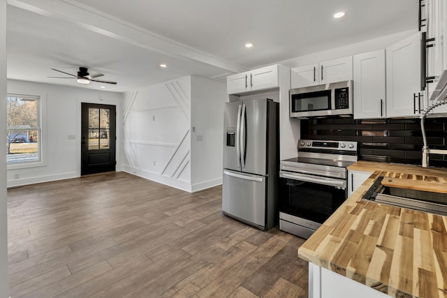 kitchen featuring white cabinetry, wooden counters, appliances with stainless steel finishes, and decorative backsplash