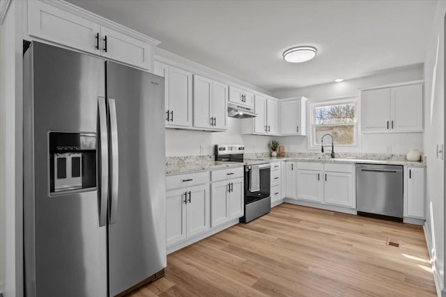 kitchen featuring light stone counters, white cabinetry, light hardwood / wood-style flooring, and stainless steel appliances