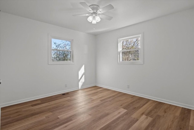 spare room featuring ceiling fan, a wealth of natural light, and wood-type flooring