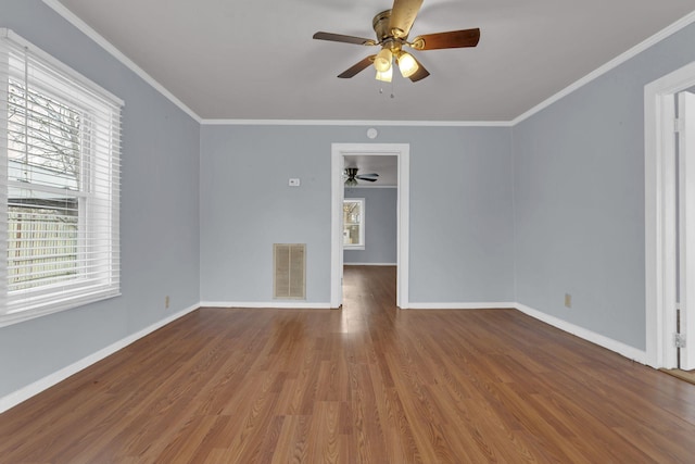 unfurnished room featuring wood-type flooring, ceiling fan, a wealth of natural light, and crown molding