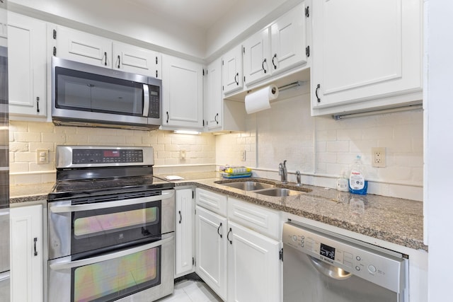 kitchen featuring white cabinets, dark stone counters, appliances with stainless steel finishes, and sink