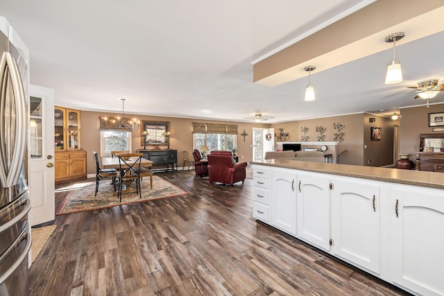 kitchen with ceiling fan with notable chandelier, white cabinets, pendant lighting, and stainless steel fridge