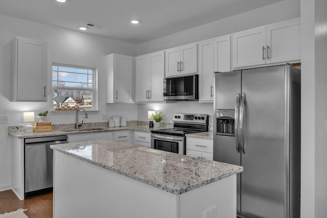 kitchen with sink, a kitchen island, white cabinets, and stainless steel appliances