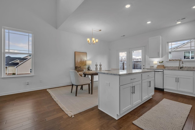 kitchen featuring a kitchen island, white cabinets, sink, and hanging light fixtures