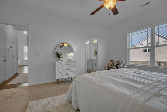 carpeted bedroom featuring ceiling fan, connected bathroom, and multiple windows