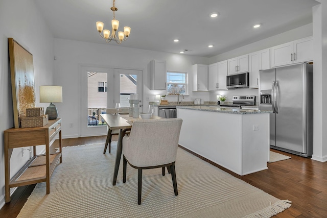 kitchen with white cabinetry, hanging light fixtures, stainless steel appliances, and a kitchen island