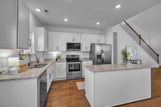 kitchen with a center island, appliances with stainless steel finishes, sink, white cabinets, and dark hardwood / wood-style floors