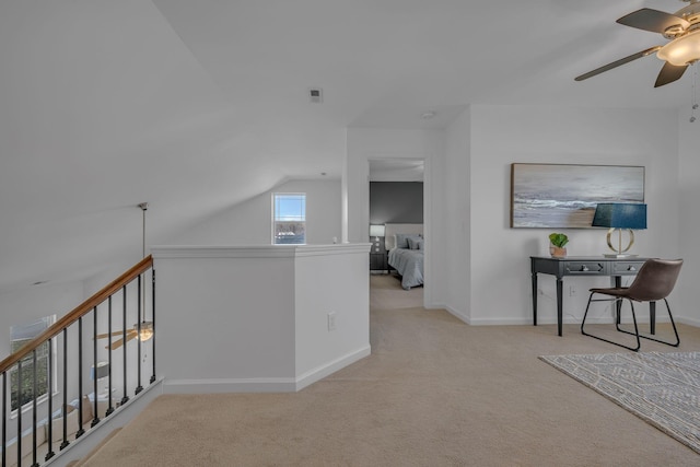 hallway with vaulted ceiling and light colored carpet