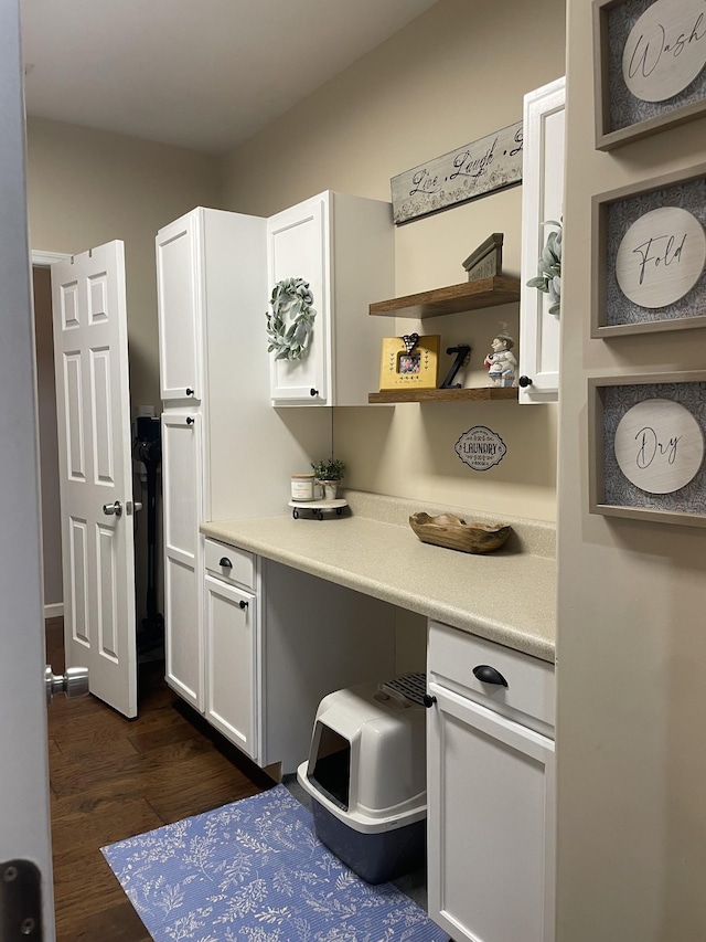 kitchen featuring white cabinetry, built in desk, and dark wood-type flooring