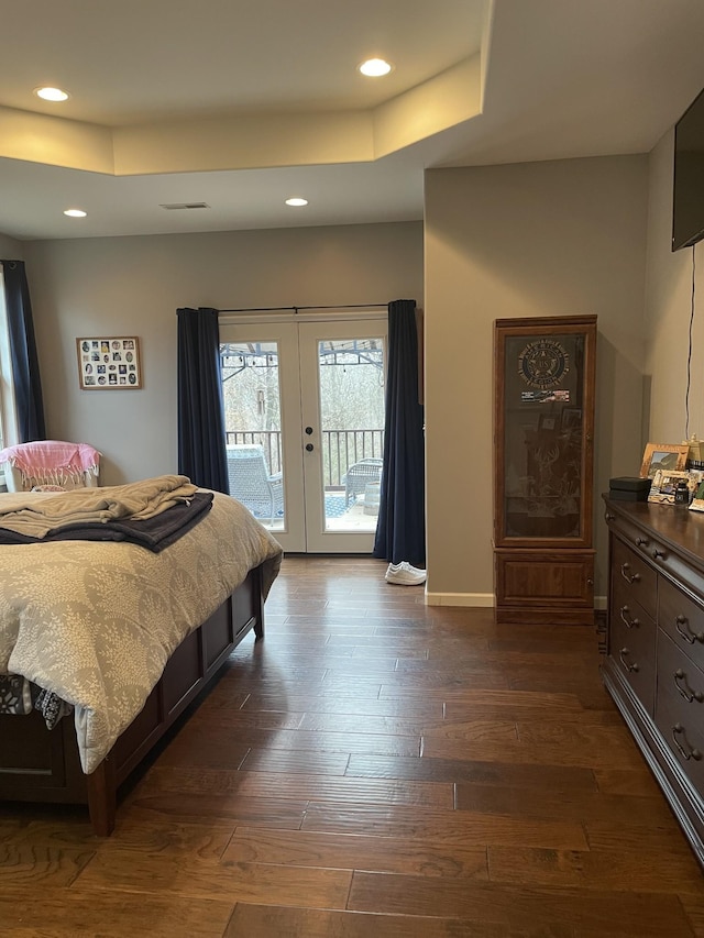 bedroom with a raised ceiling, dark wood-type flooring, access to outside, and french doors