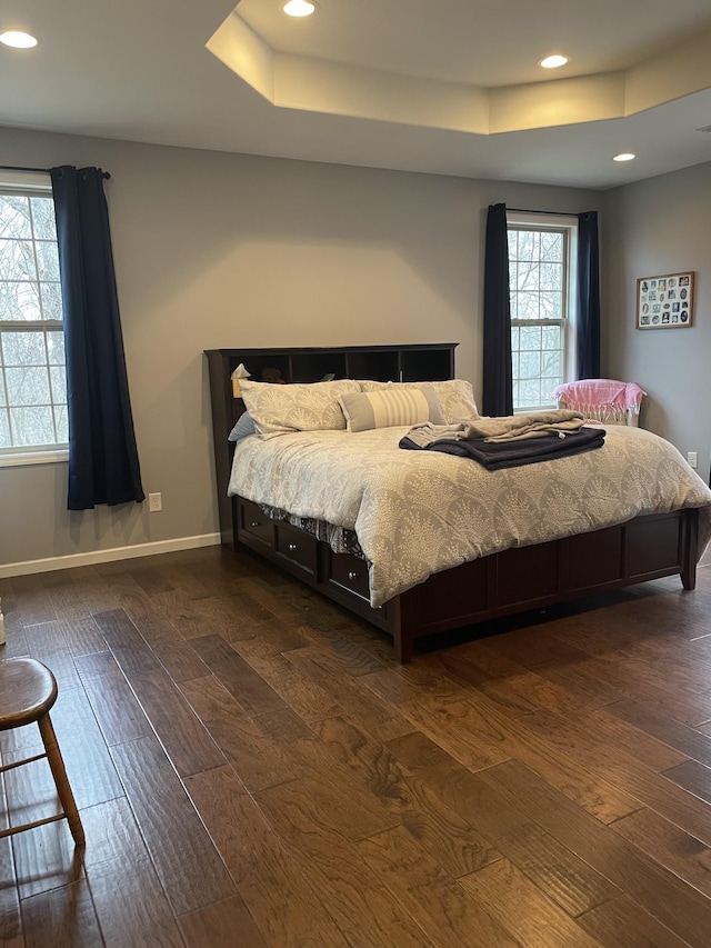 bedroom with a tray ceiling and dark hardwood / wood-style floors