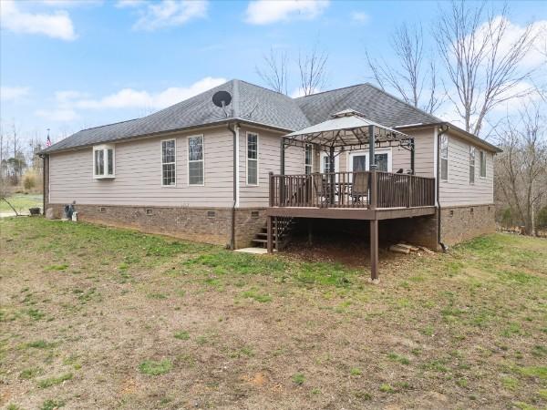 rear view of property featuring a gazebo, a yard, and a deck