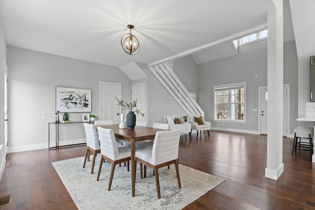 dining room with a towering ceiling, a chandelier, and dark wood-type flooring