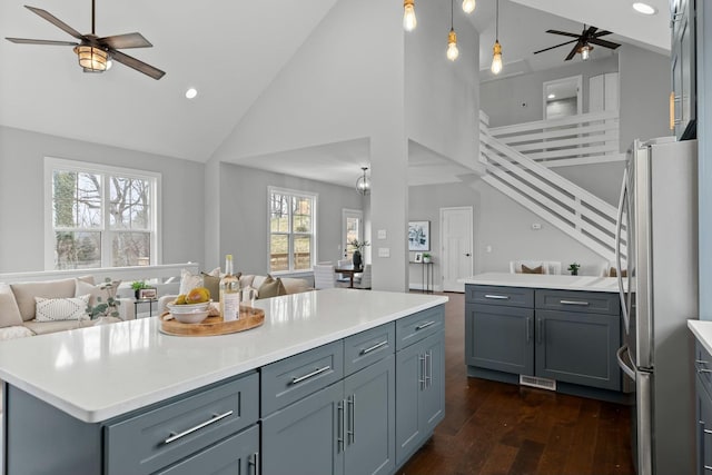 kitchen featuring a kitchen island, dark hardwood / wood-style flooring, stainless steel fridge, high vaulted ceiling, and ceiling fan