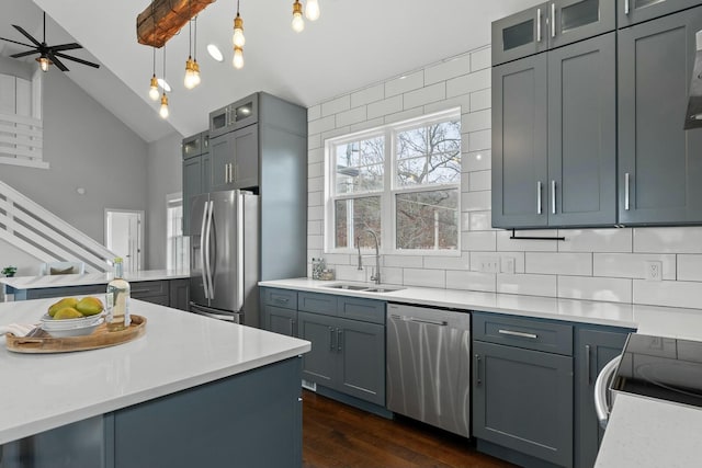 kitchen featuring appliances with stainless steel finishes, decorative backsplash, sink, pendant lighting, and vaulted ceiling