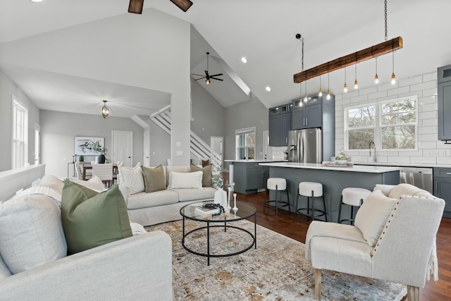 living room with dark wood-type flooring, beamed ceiling, high vaulted ceiling, and ceiling fan