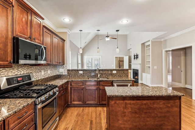 kitchen with sink, pendant lighting, dark stone counters, and stainless steel appliances