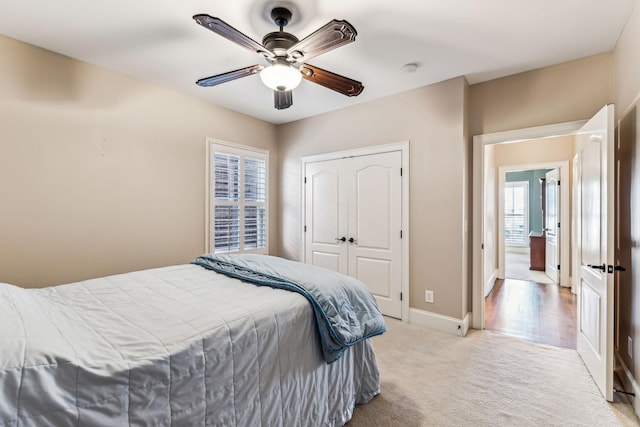 carpeted bedroom featuring a closet, ceiling fan, and multiple windows