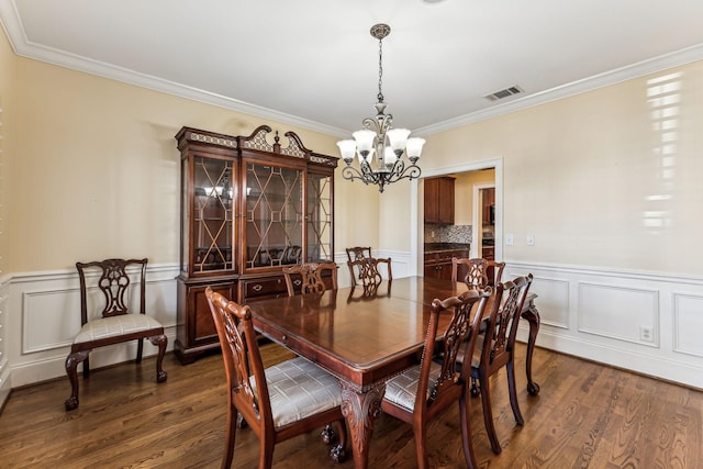 dining room with dark wood-type flooring, crown molding, and a notable chandelier