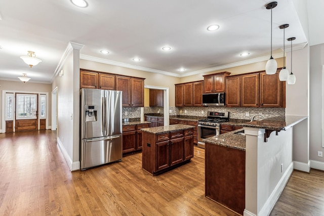 kitchen featuring pendant lighting, a kitchen island, stainless steel appliances, dark stone counters, and a breakfast bar