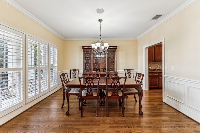 dining area with dark hardwood / wood-style floors, ornamental molding, and a chandelier