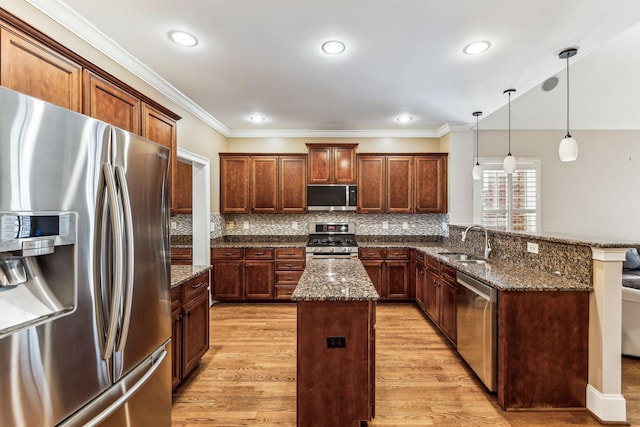 kitchen featuring decorative light fixtures, sink, dark stone counters, a center island, and stainless steel appliances