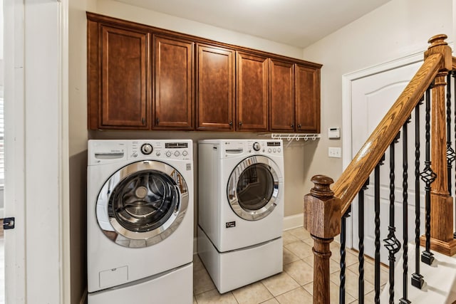 clothes washing area featuring cabinets, light tile patterned floors, and washing machine and dryer