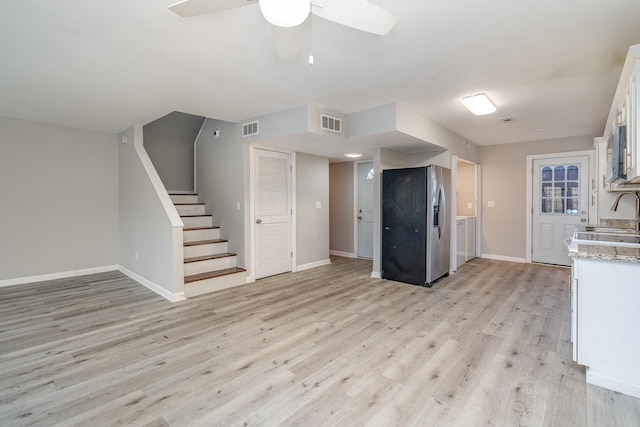 kitchen featuring stainless steel refrigerator with ice dispenser, light hardwood / wood-style flooring, sink, white cabinets, and light stone countertops