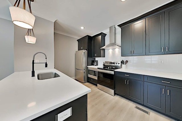 kitchen with appliances with stainless steel finishes, tasteful backsplash, sink, decorative light fixtures, and wall chimney exhaust hood