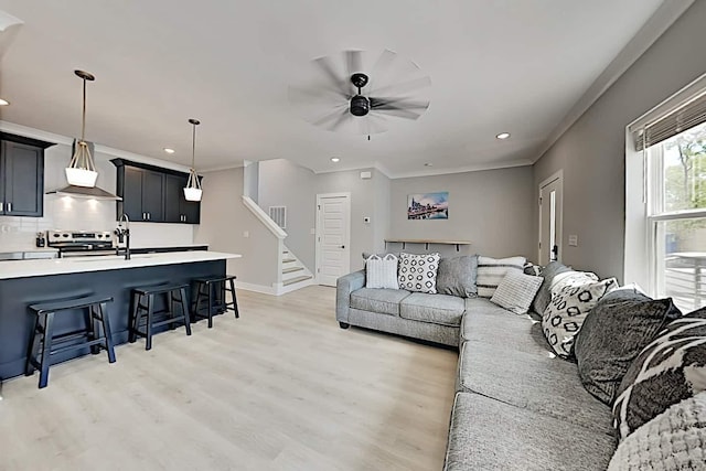 living room with light hardwood / wood-style floors, ceiling fan, and ornamental molding