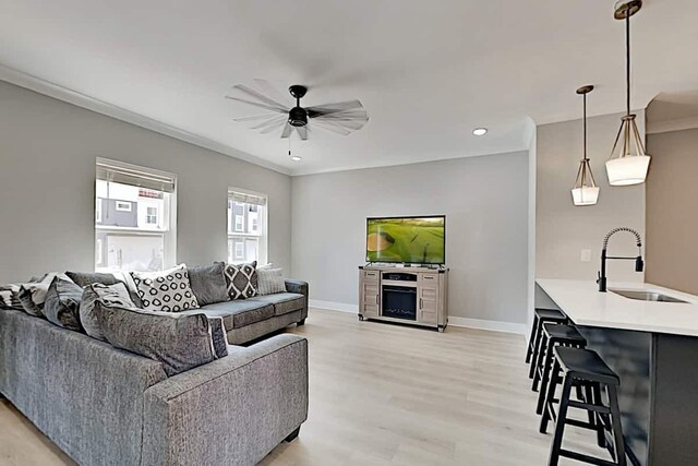 living room featuring sink, light hardwood / wood-style flooring, ceiling fan, and crown molding