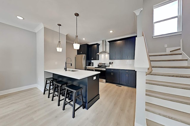 kitchen with wall chimney exhaust hood, sink, pendant lighting, stainless steel appliances, and a breakfast bar area