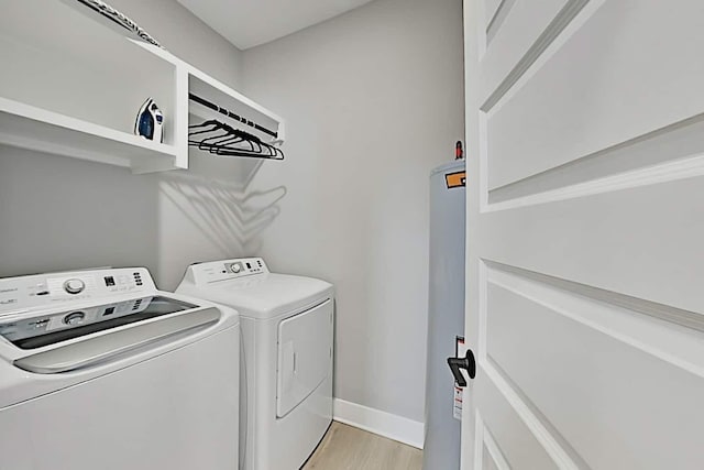 clothes washing area with separate washer and dryer, water heater, and light wood-type flooring