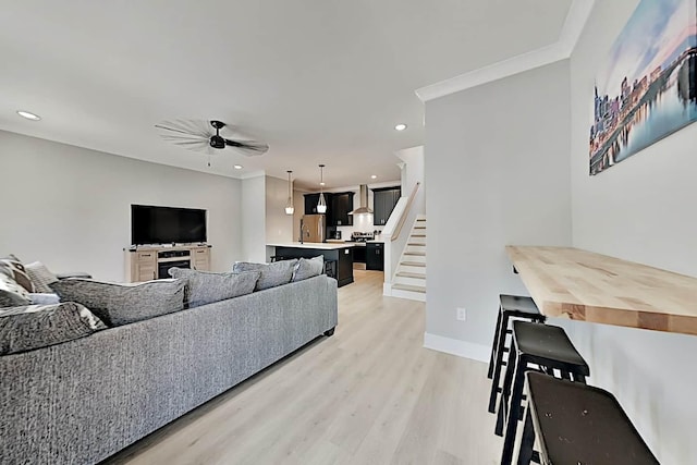 living room featuring light hardwood / wood-style floors, ceiling fan, and ornamental molding