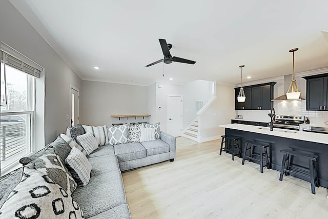 living room with ceiling fan, crown molding, and light wood-type flooring