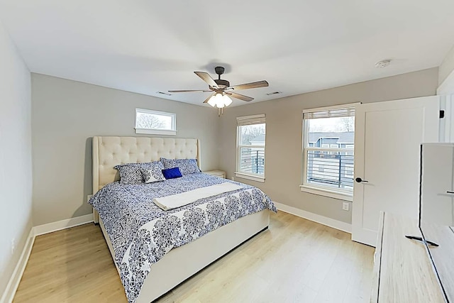 bedroom with ceiling fan, multiple windows, and light wood-type flooring