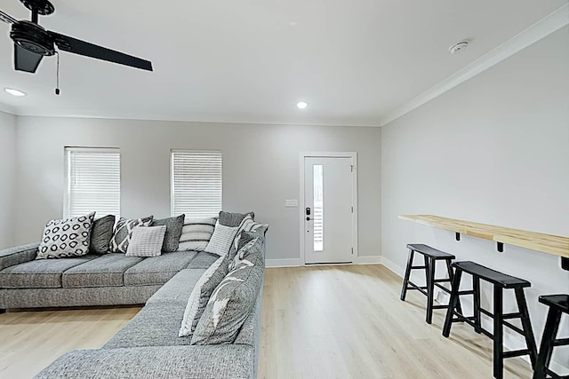 living room with crown molding, light wood-type flooring, and ceiling fan