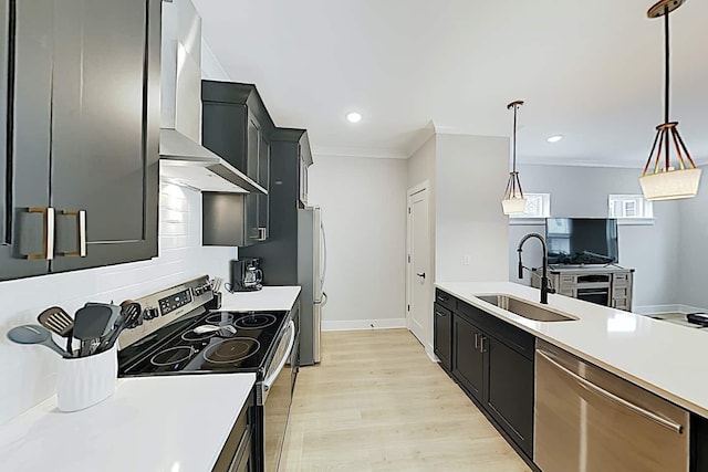 kitchen featuring appliances with stainless steel finishes, hanging light fixtures, sink, ornamental molding, and wall chimney exhaust hood