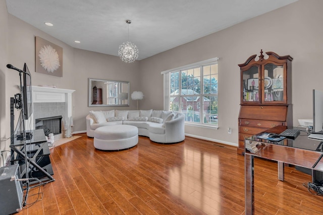 living room with hardwood / wood-style floors, an inviting chandelier, and a fireplace