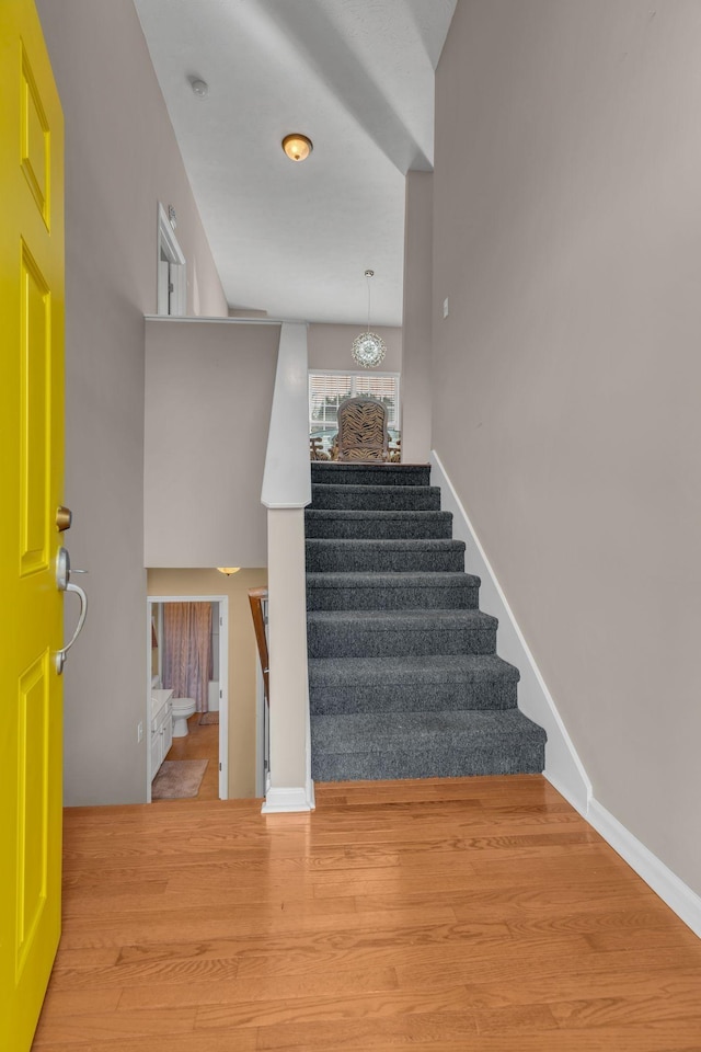 stairs featuring hardwood / wood-style flooring and an inviting chandelier