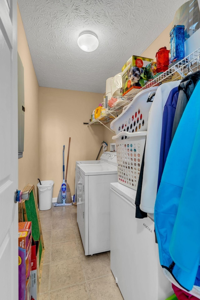 washroom with washing machine and clothes dryer, light tile patterned floors, and a textured ceiling