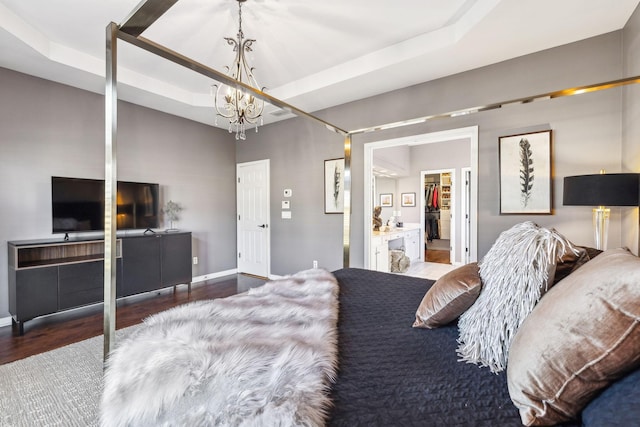 bedroom with a tray ceiling, dark hardwood / wood-style flooring, and an inviting chandelier