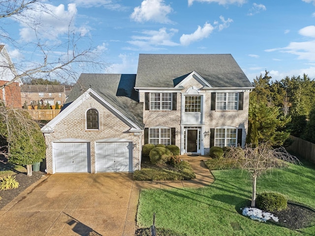 colonial inspired home featuring a garage and a front lawn