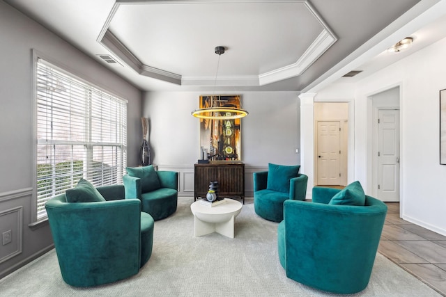 tiled living room with ornamental molding, ornate columns, and a raised ceiling