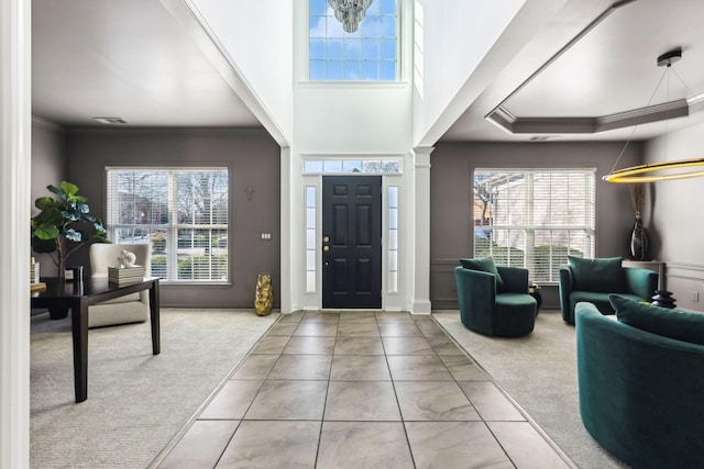 carpeted foyer entrance with crown molding and a raised ceiling