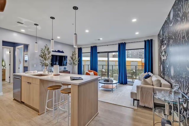 kitchen featuring sink, stainless steel dishwasher, a kitchen island with sink, and light hardwood / wood-style floors