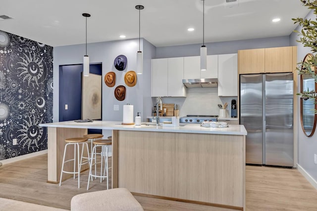 kitchen with an island with sink, light wood-type flooring, white cabinetry, and stainless steel refrigerator