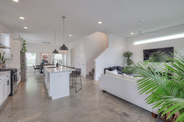 kitchen with white cabinets, a center island with sink, stainless steel appliances, and a healthy amount of sunlight