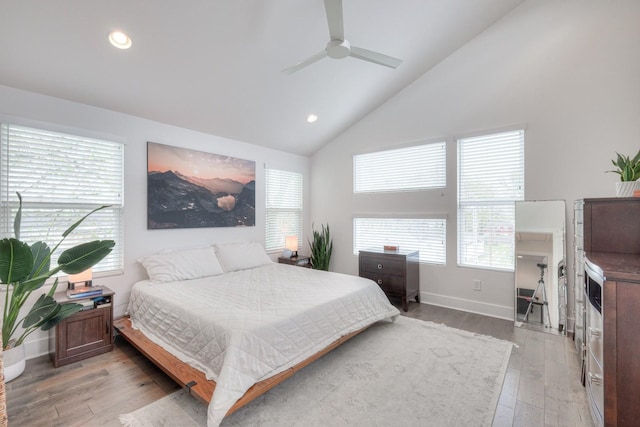 bedroom with ceiling fan, light hardwood / wood-style floors, multiple windows, and high vaulted ceiling